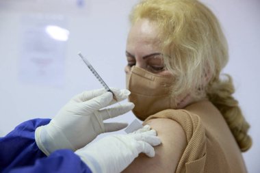 BUCHAREST, ROMANIA - 27 Aralık 2020: Avrupa Aşı Kampanyası 'nın ilk gününde bir tıp personeli covid aşıyı aldı.