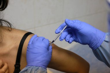 BUCHAREST, ROMANIA - 27 Aralık 2020: Avrupa Aşı Kampanyası 'nın ilk gününde bir tıp personeli covid aşıyı aldı.