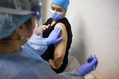 BUCHAREST, ROMANIA - 27 Aralık 2020: Avrupa Aşı Kampanyası 'nın ilk gününde bir tıp personeli covid aşıyı aldı.