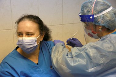 BUCHAREST, ROMANIA - 27 Aralık 2020: Avrupa Aşı Kampanyası 'nın ilk gününde bir tıp personeli covid aşıyı aldı.