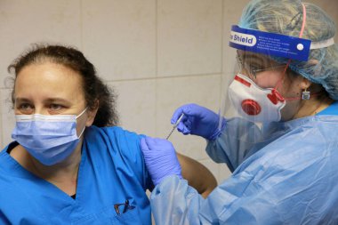 BUCHAREST, ROMANIA - 27 Aralık 2020: Avrupa Aşı Kampanyası 'nın ilk gününde bir tıp personeli covid aşıyı aldı.