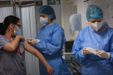 BUCHAREST, ROMANIA - 27 Aralık 2020: Avrupa Aşı Kampanyası 'nın ilk gününde bir tıp personeli covid aşıyı aldı.