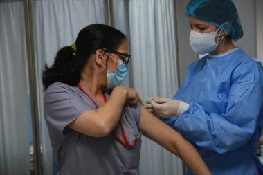 BUCHAREST, ROMANIA - 27 Aralık 2020: Avrupa Aşı Kampanyası 'nın ilk gününde bir tıp personeli covid aşıyı aldı.