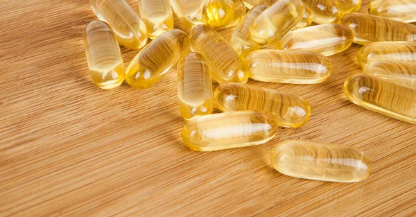 Cod liver oil omega 3 gel capsules on the wooden table desk isolated on white background