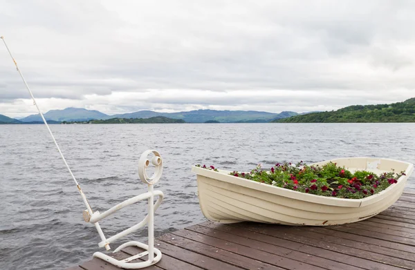 Boot als bloem pot en ijzer visser op pier op lake — Stockfoto