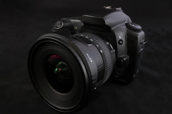 Eine schwarze Kamera mit Weitwinkelobjektiv isoliert auf schwarzem Hintergrund — Stockfoto