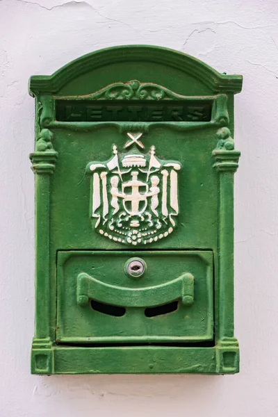 Green metal antique mailbox on a white house wall in old NIcosia, island of Cyprus