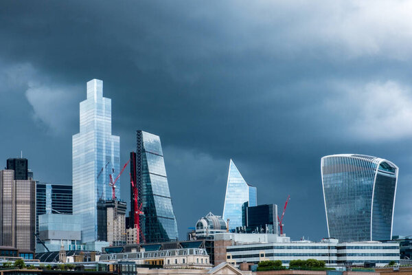 City of London busines district Shiny Skyscrapers set against a dramatic stormy sky in the middle of british summer.