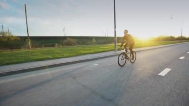 Adam sürme sabit vites bisiklet gün batımında yolda