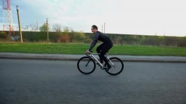 Adam sürme sabit vites bisiklet gün batımında yolda