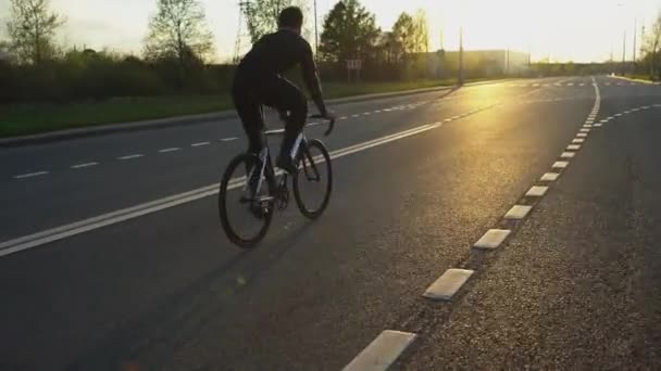 Muž na koni kotvené zařízení kolo na silnici při západu slunce — Stock video