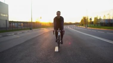 Adam sürme sabit vites bisiklet gün batımında yolda
