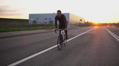 Adam sürme sabit vites bisiklet yavaş gün batımında yolda
