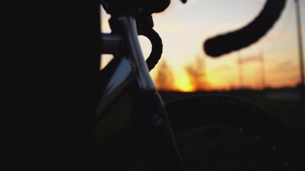 Человек едет на велосипеде с фиксированной передачей на дороге на закате в замедленной съемке — стоковое видео