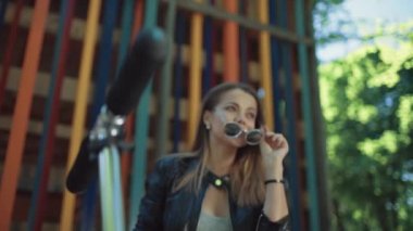 Güzel genç mutlu kadın sokakta scooter ile kahve içme