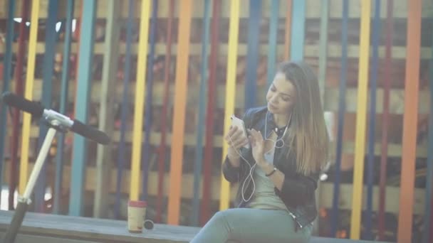 Poslech hudby dívka ze smartphonu s koloběžkou — Stock video