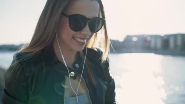 Bella ragazza bruna che ascolta musica sul fiume con il telefono — Video Stock