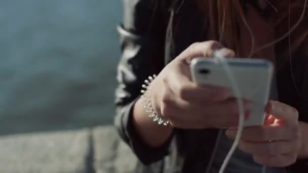 Mooie brunette meisje luisteren muziek op de rivier met de telefoon — Stockvideo