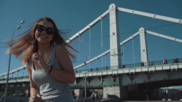 Chica feliz corre en el fondo del puente en cámara lenta — Vídeo de stock