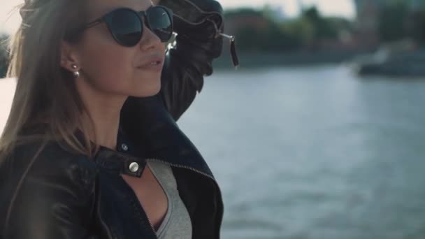 Girl in the wind sits on the waterfront in slowmotion — Stock Video