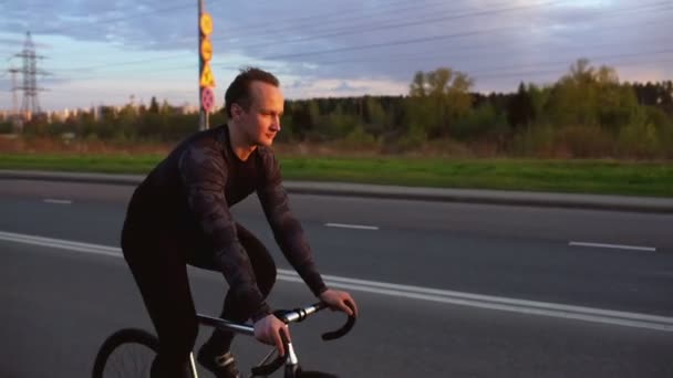 Man som Red fixed gear cykel på vägen vid solnedgången — Stockvideo