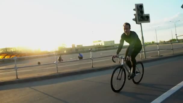 Muž na koni kotvené zařízení kolo na silnici při západu slunce — Stock video