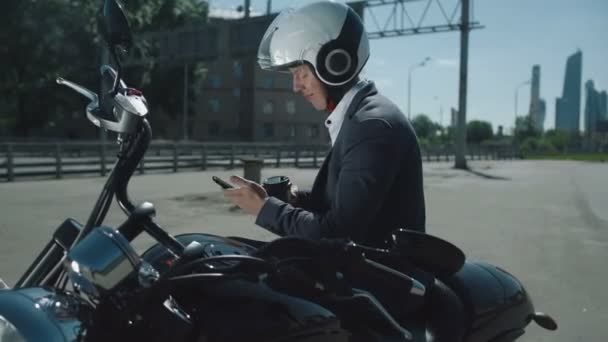 Hombre de negocios en una motocicleta mira el teléfono inteligente . — Vídeos de Stock