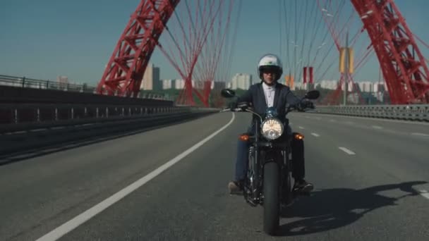 Чоловік їде на мотоциклі під мостом у місті — стокове відео