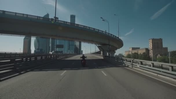 Man köra motorcykel under bron i en stad — Stockvideo