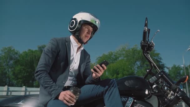 Homme d'affaires sur une moto regarde le téléphone intelligent . — Video