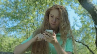 Kızıl saçlı kız seyir telefon elma bahçesi içinde