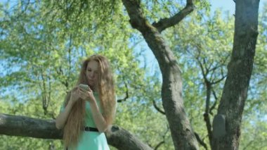 Kızıl saçlı kız seyir telefon elma bahçesi içinde