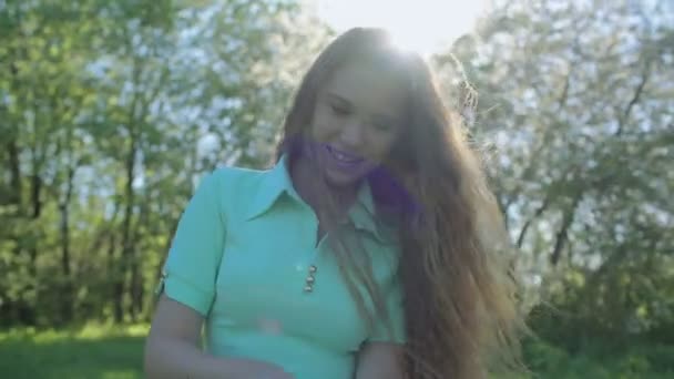 Dziewczyna z długimi rudymi włosami wygląda tablet apple ogród — Wideo stockowe