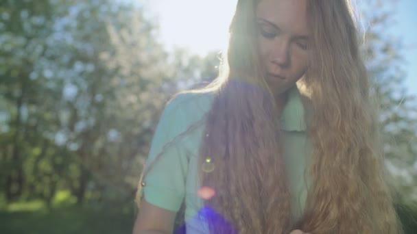 Meisje met lang rood haar kijkt naar tablet in apple tuin — Stockvideo