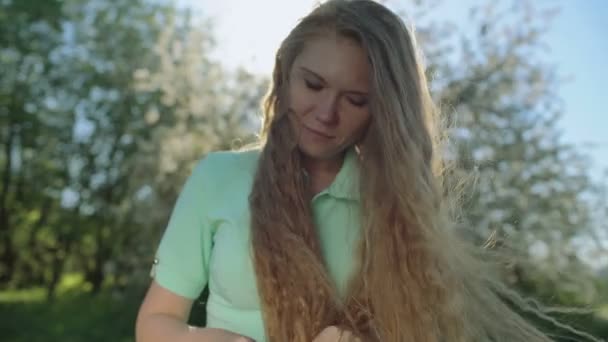 Menina com cabelos vermelhos longos olha para tablet no jardim da maçã — Vídeo de Stock