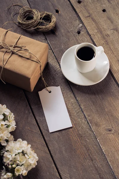 Gift box, coffee cup and blossom on a rustic background