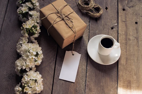 Caixa de presente, xícara de café e flor em um fundo rústico — Fotografia de Stock