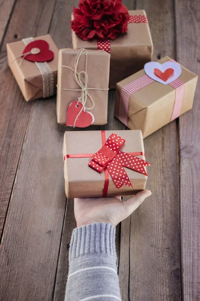 Dámské ruce držící dárek na dřevěném stole — Stock fotografie