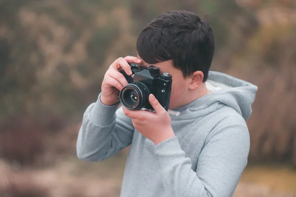 Jovem rapaz atirando com câmera vintage — Fotografia de Stock