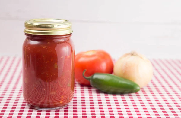 Kırmızı Gingham Masa örtüsü üzerinde salsa. Ev Canning Kavanozunda.