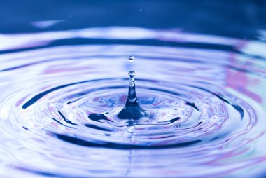 Sivri Su Damlacıkları Kırmızı ve Mavi Yansımalı Bir Su Havuzuna Düşer