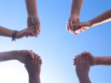 Çemberde dua eden bir grup insan ellerini tutarak haçın şeklini alıyorlar.