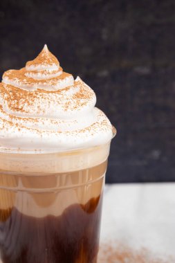 Krem şantili tek kullanımlık plastik bardakta buzlu kahve.