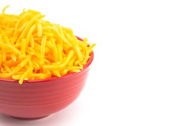 Beyaz arka planda bir kase ızgara Cheddar peyniri.  