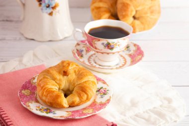 Taze pişmiş tereyağlı kruvasan Sıcak Siyah Kahveyle Kahvaltı Masasına Yattı