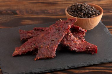Köhne ahşap bir masa üzerinde bir yığın Black Pepper Biftek Kurutulmuş eti.