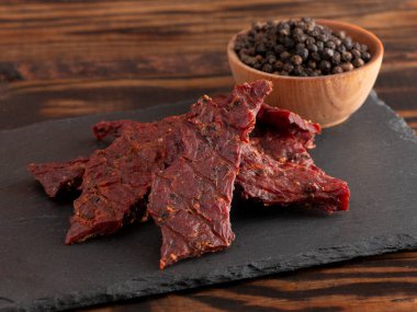 Köhne ahşap bir masa üzerinde bir yığın Black Pepper Biftek Kurutulmuş eti.