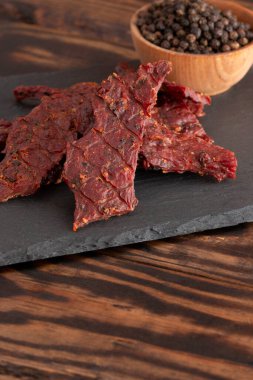 Köhne ahşap bir masa üzerinde bir yığın Black Pepper Biftek Kurutulmuş eti.