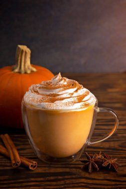 Tahta bir masada, şeffaf bir kupada balkabağı aromalı latte.