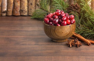 Tahta bir masada taze yuvarlak kırmızı kızılcık kasesi.